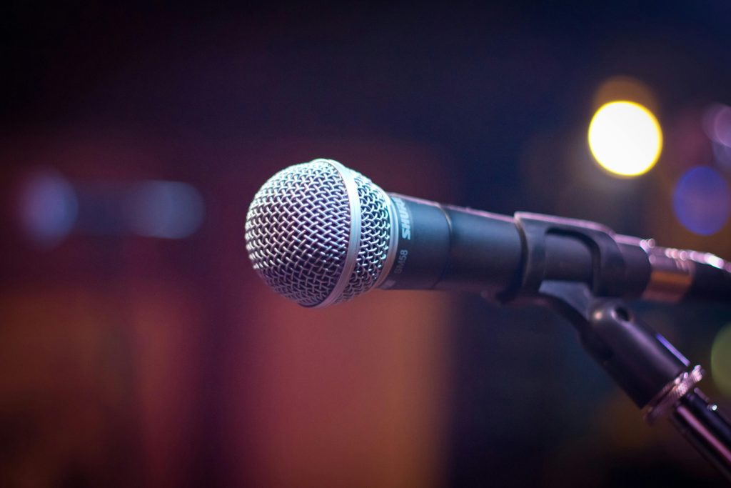 pexels-photo-164829-164829 Dynamic microphone on stand with blurred stage lights in background.